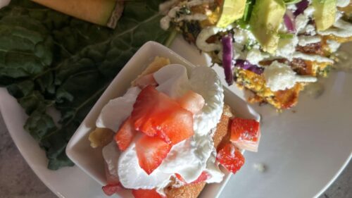 Southwestern Style Breakfast, Chorizo Hashbrown Quiche Topped with Avocado alongside a small piece of Tres Leches Cake topped with Whipped Cream and Fresh Strawberries
